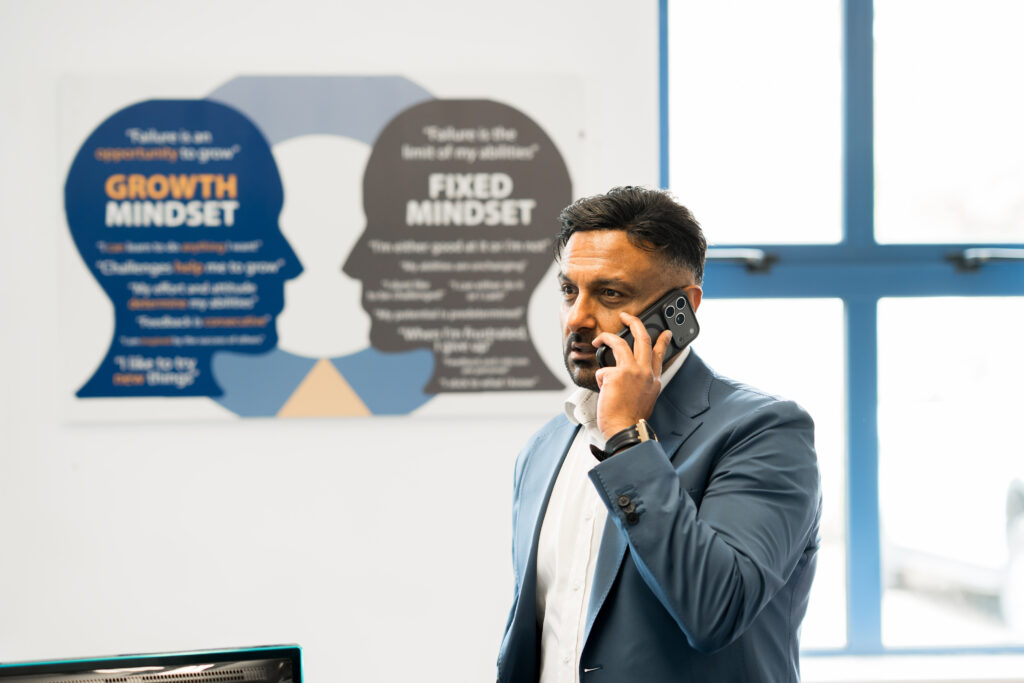 Brij Thankey, founder in office on phone call in his office with growth mindset poster in background