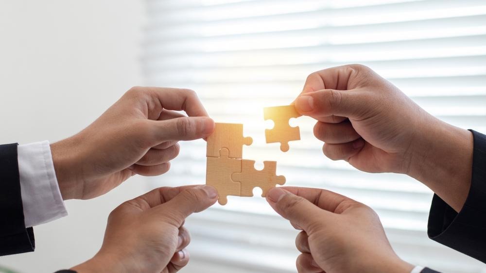 Colleagues connecting puzzle pieces to represent shared direction and coordinated execution emanating from building a high-performing team